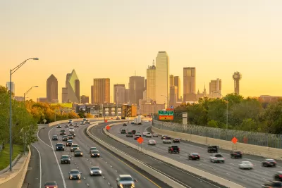 View of Dallas city skyline with moderately busy freeway in foreground at twilight.