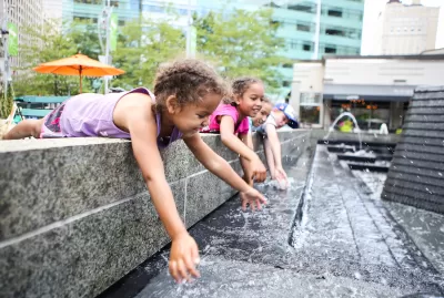 Young girls dipping their hands in an outdoor decorative water fountain