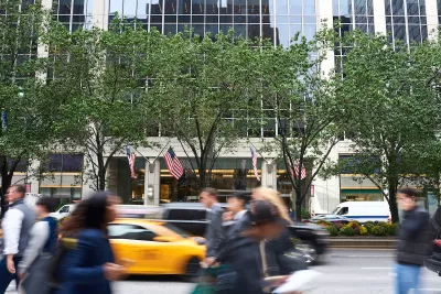 Blurred pedestrians walkingon NYC sidewalk with blurred yellow cab in background.