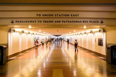 View looking down indoor concourse at Los Angeles Union Station with “To Union Station East” and “Passageway to Trains and Patsaouras Bus Plaza” signs.