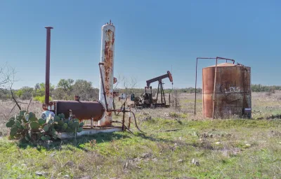 Rusty abandoned oil well and equipment with prickly pear cactus next to it in West Texas.