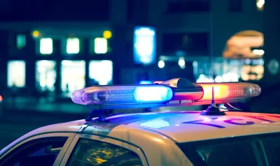 Nighttime view of blue and red lights on top of a white police car.