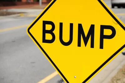 Close-up on yellow sign with black 'BUMP' letters indicating speed bump ahead.