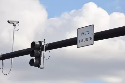 Traffic light on overhead pole with traffic camera and "Photo Enforced" sign