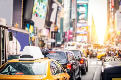 Blurred view of NEw York City traffic near Times Square with yellow cabs and black cars.