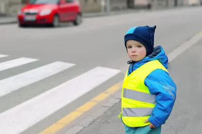 Child wearing yellow reflective safety vest looking before crossing street.