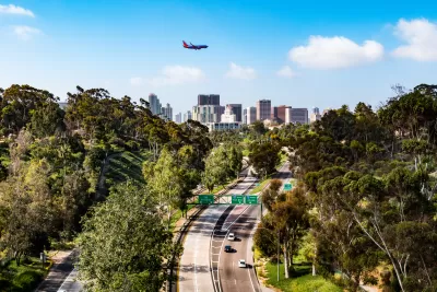 An airplane flies over the Cabrillo Freeway (State Route 163) as it passes through Balboa Park and into the downtown area of San Diego, California.