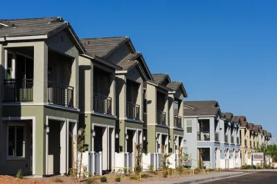 Row of newly constructed green two-story townhomes.