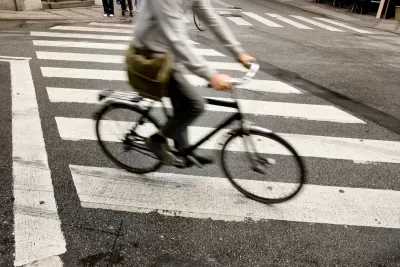 Person on bike riding across zebra crosswalk in city.