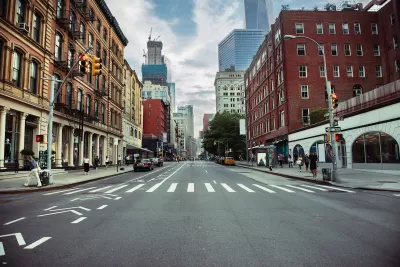 New York City street with painted bike lane and crosswalk flanked by brick buildings.