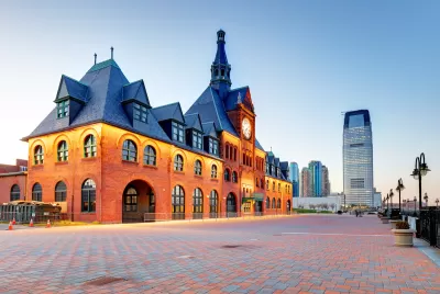 Red brick historic Central Railroad of New Jersey Terminal, Liberty State Park, New Jersey with glass high-rise building in background.