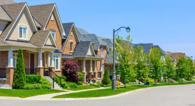 Row of single-family houses on suburban street on sunny day.