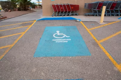 A handicap parking space with yellow painted wheelchair symbol and yellow hatched space on both sides.