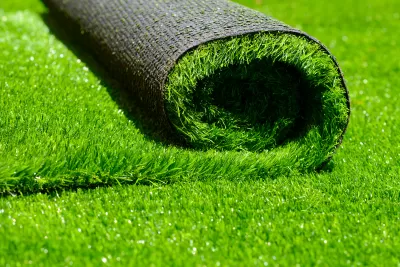 Close-up of roll of green artificial turf laying on more artificial turf.
