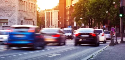 Blurred cars driving down road with European road signs visible.
