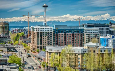 View of multistory buildings under construction in downtown Seattle, Washington with Space Needle and Mount Rainier in background.