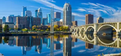 Minneapolis, Minnesota skyline with river and bridge in foreground.