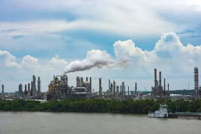 Cheical plant with shite steam coming out of metal towers on riverbank in Louisiana.