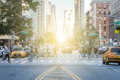 Busy crosswalk with people and bikes in New York City on a bright afternoon.