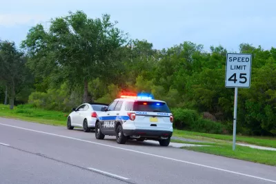 White and blue police SUV pulling over small white sedan in front of 45 mph speed limit sign.