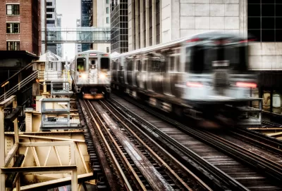 View of two blurred Chicago el trains passing on elevated track between buildings