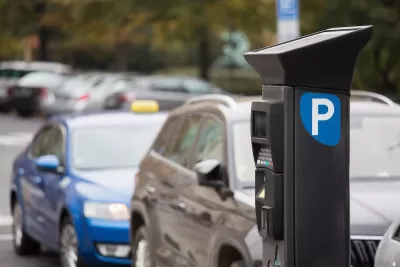 Parking payment machine on street with blurred cars parked in background.