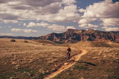 Person on mountain bike biking on trail in Colorado with mountains in background
