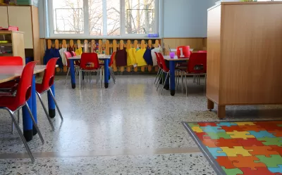 Empty kindergarten classroom with colorful chairs and floor mats.