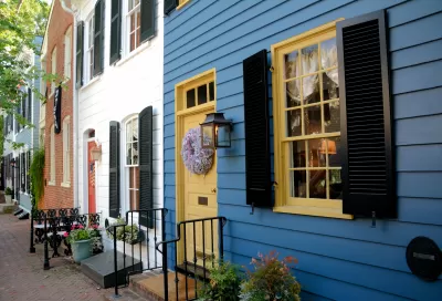Line of blue, white, and red brick row homes with colorful doors and iron railings.