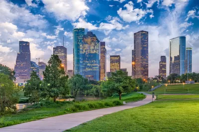 Green lawn and walkway in downtonw Houston park with skyline in background.