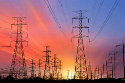 High voltage power line towers sillhouetted against colorful sunset sky.