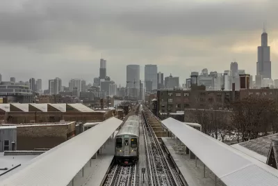 Train on elevated track on snowy city landscape with Chicago skyline in background.