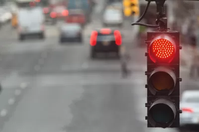 Close-up on red traffic light with blurred street in background.