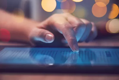 Close-up of hand scrolling through text website on tablet lying on table.