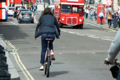 Woman rides a bike on street in London, UK.