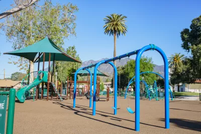 Blue and green playground equipment in Los Angeles with palm tree and mountains in background