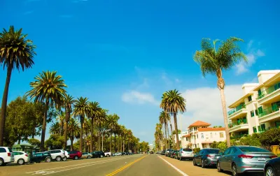 Wide street in Santa Monica, California with cars parked on either side and tall palm trees lining the street on a sunny day.