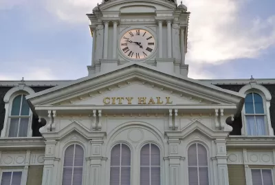 White neoclassical building with cupola and City Hall lettering on front.