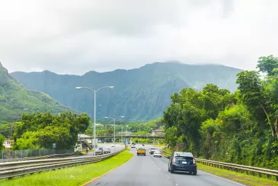 Traffic on Hawaii highway with green mountains in background