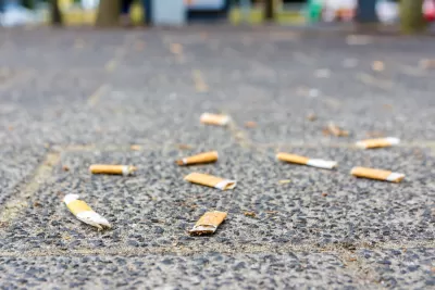 Flattened cigarette butts littering a sidewalk