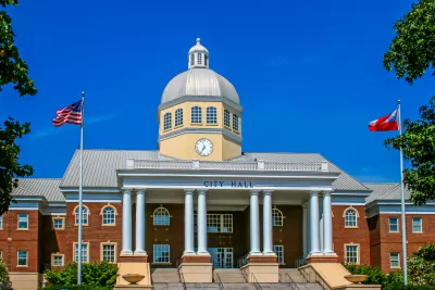 Neoclassical city hall building with dome, columns, and American flags flying in front