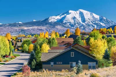 Residential neighborhood in Colorado with fall foliage and snowy mountains in background.
