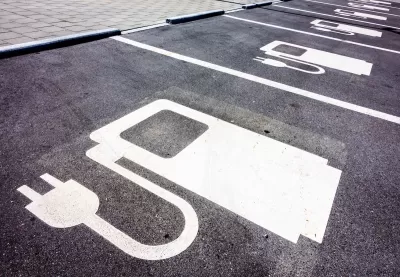 Close-up of white electric car charging symbol on black pavement in parking spaces.