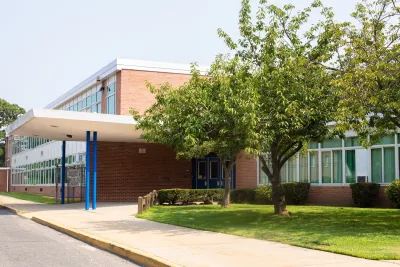 Brick school building with mid-sized tree on front lawn.