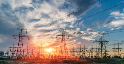 View of power towers at electric distribution substation against colorful sunset sky.