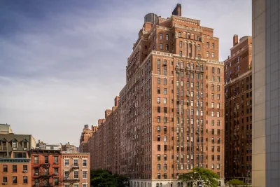 Tall red brick public housing building in New York City surrounded by shorter apartment buildings.