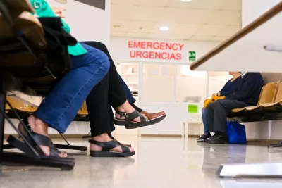 Close-up on the bottom half of people sitting in a hospital waiting room.