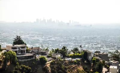 View of large mansions in Hollywood hills with downtown Los Angeles skyline in background.