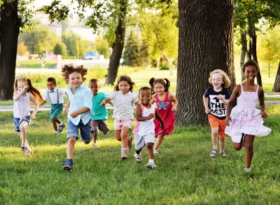 Group of children running toward the camera on a green lawn