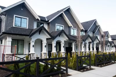ROwn of grey and white townhomes with gabled roofs and front porches.